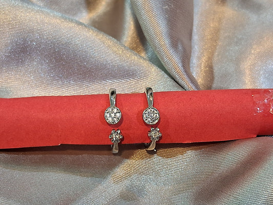 Silver earrings with gemstones on a red card against a textured fabric background