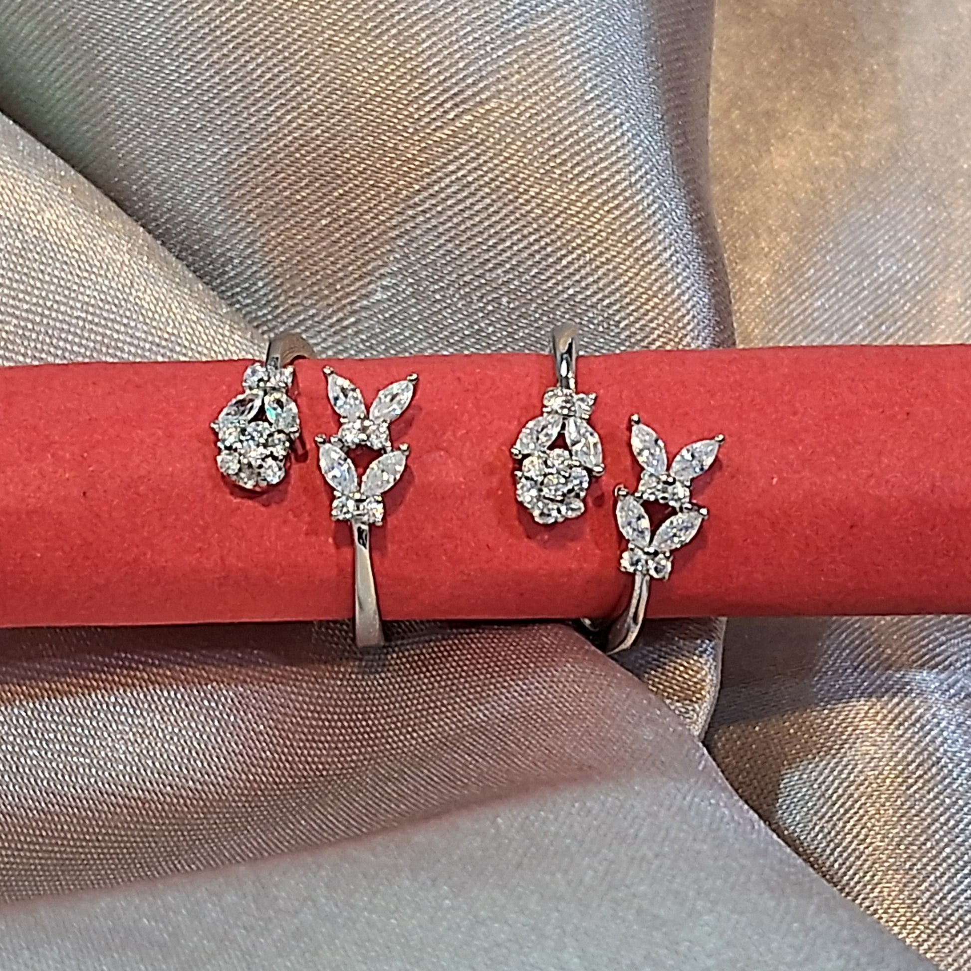 Pair of silver toerings on a red stick against a beige fabric background