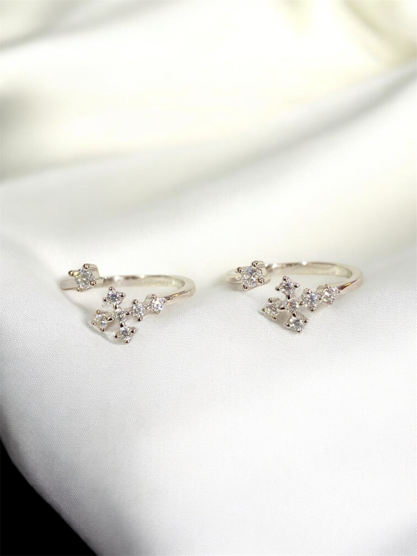 Pair of silver earrings with clear gemstones on a white surface