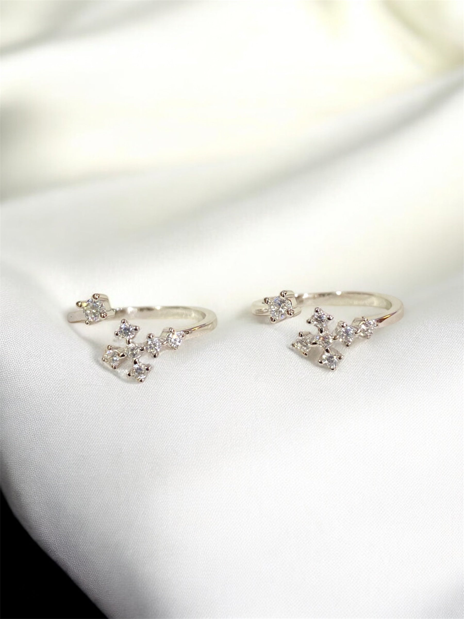 Pair of silver earrings with clear gemstones on a white surface