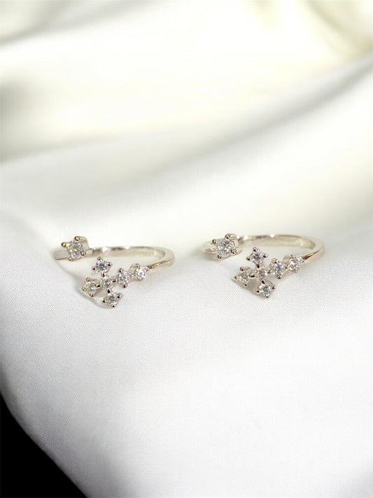 Pair of silver earrings with clear gemstones on a white surface